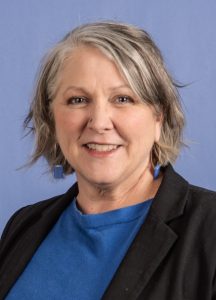 Headshot of woman wearing a blue top and dark jacket