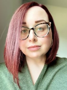 Headshot of woman wearing a green top and glasses